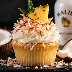 Vanilla cupcake covered in toasted coconut with a pineapple wedge
