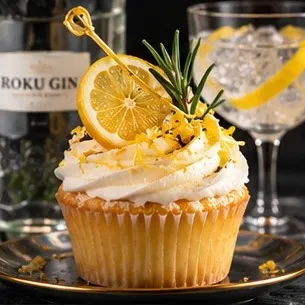 Lemon cupcake topped with a lemon slice, zest and a rosemary sprig